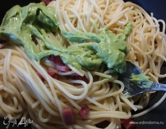 Готовые спагетти выложить в сковороду с колбасками (небольшое количество воды, в которой они варились, отобрать). Соус из авокадо выложить в спагетти, добавь воду для более сочной консистенции, размешать.
