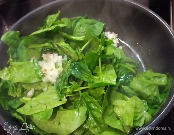 Шпинат для соуса нужно припустить. Для этого нужно разогреть масло и пассеровать мелко рубленый лук и чеснок до прозрачности. Добавить промытый и обсушенный шпинат. Он тут же начинает «таять», становится мягким и отдает свой ореховый аромат. Параллельно поставить вариться спагетти (у меня из ц/з муки).