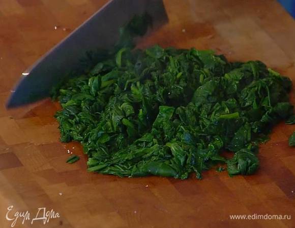 Приготовить начинку: шпинат опустить на 2‒3 минуты в кипящую воду, откинуть на дуршлаг, дать стечь лишней воде и промокнуть шпинат бумажным полотенцем, затем мелко порубить и немного остудить.