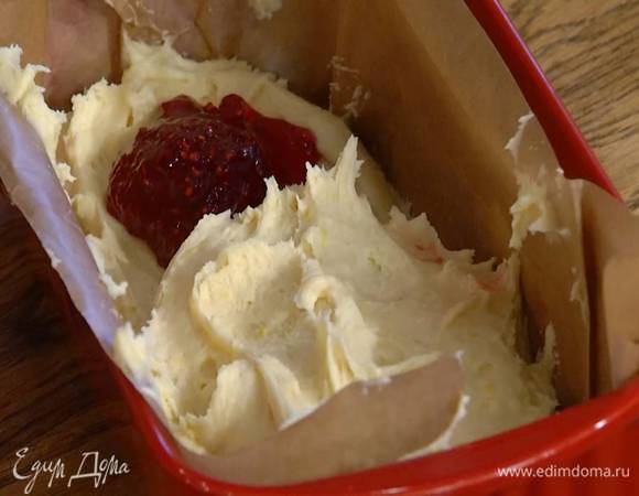 Продолговатую форму для выпечки смазать оставшимся сливочным маслом и выстелить бумагой для выпечки, по дну формы распределить половину теста, по центру, отступая от краев, выложить малиновый джем, а сверху оставшееся тесто.