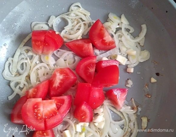 Помидор вымыть, нарезать крупными кубиками. Добавить в сковородку к луку, перемешать. Огонь выключить. Помидор должен остаться целым, лишь немного прогреться.