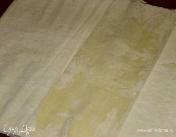 Из теста фило начинаем сворачивать трубочки. Работаем уверенно и быстро, чтобы тесто не успевало высохнуть. Кисточкой смажьте лист теста сливочным маслом. Сложите 1/3 теста к середине, накройте другой стороной сложенные слои.