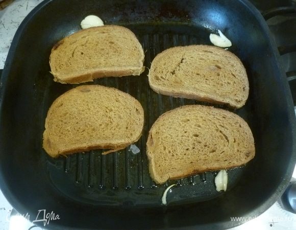 Разогреть сковороду гриль (или обычную). Плеснуть масла. Два зубчика чеснока очистить и раздавить плоской стороной ножа, выложить в сковороду и «погонять» по сковороде вилкой, чтобы масло вобрало в себя аромат чеснока. Выложить ломтики хлеба и обжарить с двух сторон.