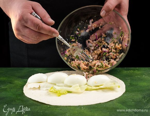 Собираем роллы. Расстелите лаваш, выложите на него салатные листья. Сверху положите несколько ложек салата и дольки яиц.<br />
 