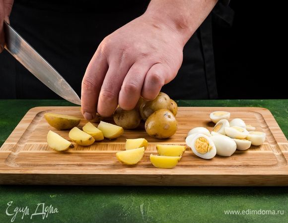 Тщательно вымойте и отварите картофель. Остудите и нарежьте пополам. Отварите перепелиные яйца. Остудите в холодной воде и очистите. Разрежьте пополам.<br />
 