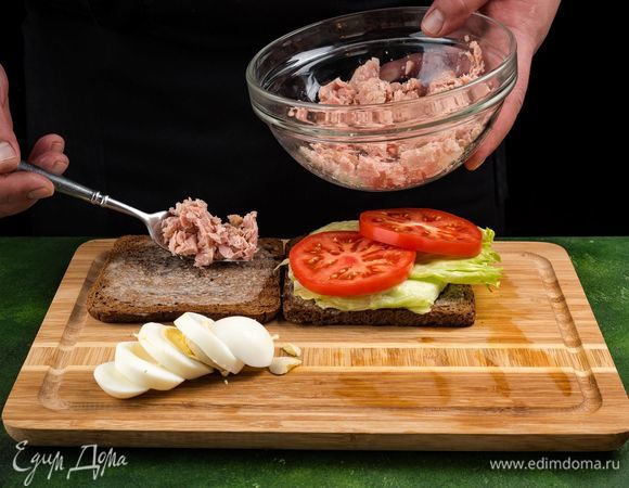 На одну половину тоста выложите листья салата и помидор, на другую — тунца и яйцо.<br />
 