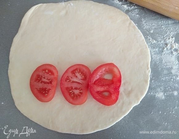 Зрительно разделить лепешку на 2 части. Заполнять будем одну часть. Первый слой — кружки помидора. Поперчить, посолить немного.
