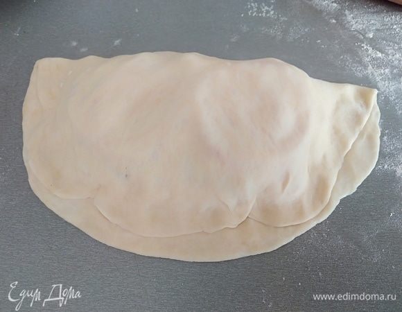 Края лепешки смочить водой. Завернуть один край на другой. Прижать пальцами.