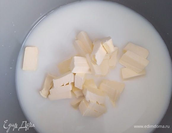 Духовку разогреть до 220°C. В кастрюлю налить молоко, воду, соль, сахар и нарезанное кубиками сливочное масло. Дать закипеть, помешивая лопаткой. Выключить плиту.
