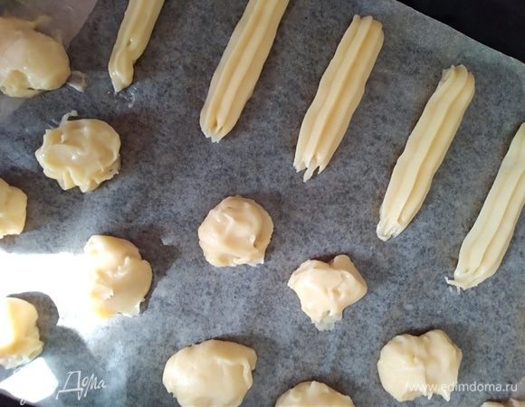 Тонким слоем смазать противень или бумагу для выпечки растительным маслом. Отсадить из теста круглые заготовки для профитролей или удлиненные для эклеров. Можно сделать, как я. Чайную ложку обмакнуть в воду, набрать тесто, поместить на бумагу. Пригладить смоченным в воде пальцем. Получается около 20 средних профитролей.