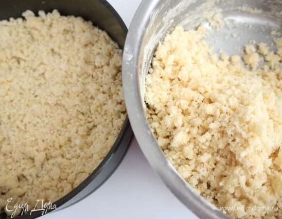 Отделить третью часть крошки (сделать это «на глаз»), поместить аккуратно в форму, дно которой лучше застелить бумагой для выпечки. Я этого не делала, лишь слегка смазала дно сливочным маслом, но это более трудный путь для того, чтобы после выпечки отделить корж от формы.