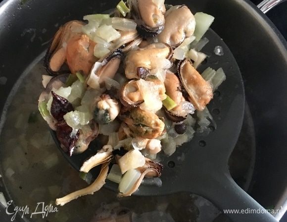 Теперь берем шумовку и перекладываем мидии вместе с овощами (только специи вынуть) прямо в соус бешамель. Добавляем понемногу жидкость, в которой варились мидии, перемешиваем. Густоту соуса регулируем под свой вкус. Я добавила практически весь соус на белом вине в бешамель и мидии. В идеале мидии должны быть полностью «окутаны» соусом, но, с другой стороны, конечно, не плавать в соусе, как в океане.