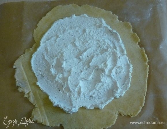 Выложить тесто на кусок пергамента, раскатать прямо на нем. Распределить сырную массу, не доходя до краев 3 см.