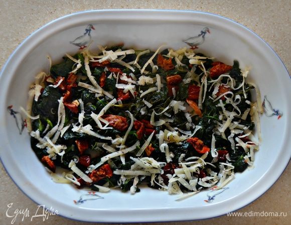 Форму для запекания смазать оливковым маслом, выложить шпинатную смесь и посыпать половиной тертого пармезана.