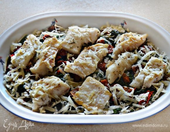 Сверху выложить филе трески, сбрызнуть оливковым маслом и посыпать оставшимся сыром. Запекать 7–10 мин. в разогретой до 180°C духовке до расплавления сыра.