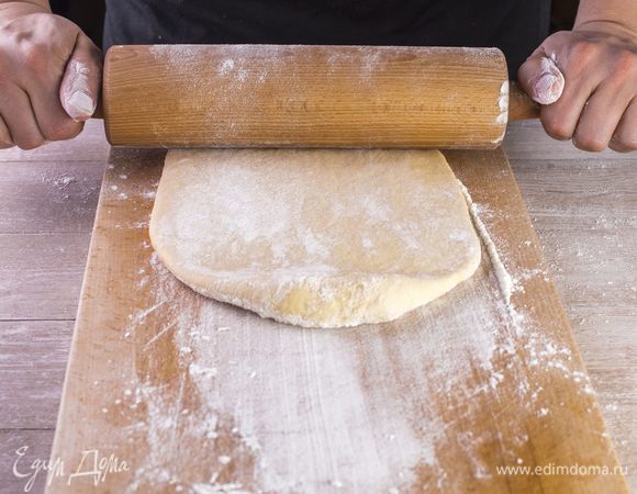 Разделите тесто на несколько частей, раскатайте скалкой в продолговатые пласты по ширине чуть больше, чем сосиска.