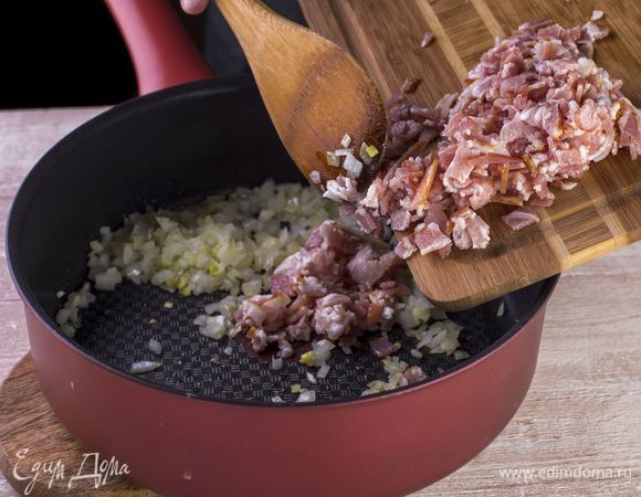 Нарежьте бекон ломтиками, смешайте с луком и жарьте до румяной корочки.