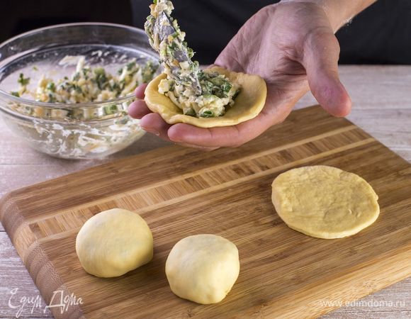 Сформируйте из теста несколько шариков, с помощью пальцев разомните на небольшие круглые лепешки. На каждую лепешку положите по 1 ст. л. начинки.