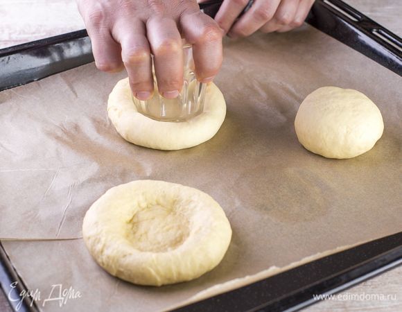 Разделите тесто на 8–10 статей, сформируйте крурглые толстые лепешки и при помощи стакана сделайте в них углубления.