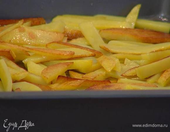 Обжаренный картофель переложить в глубокий противень и запекать в разогретой духовке 15‒18 минут.