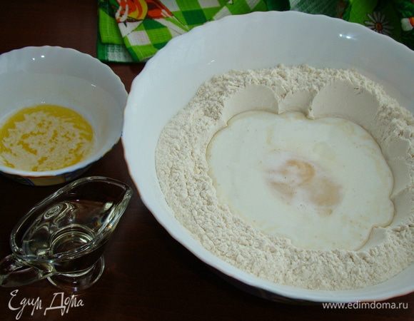 В муке сделать лунку, влить молоко, добавить яйцо, растительное масло и растопленное остывшее сливочное масло.