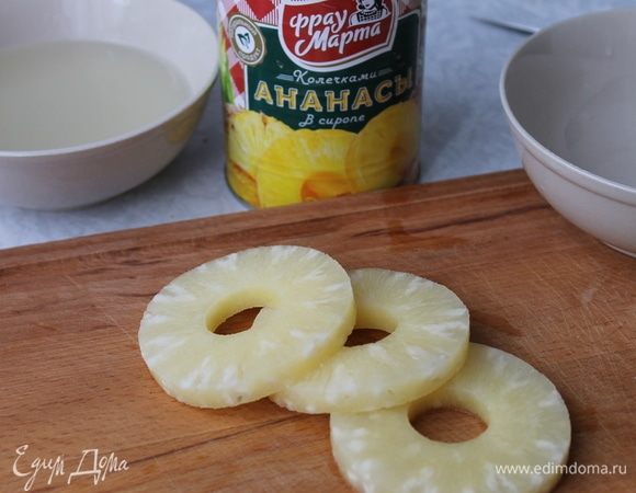 Пока будет остывать бисквит, у вас есть время приготовить ананасовую прослойку и крем. С ананасов слейте сироп, а колечки или кусочки ананасов нарежьте на мелкие кубики. 4 кружочков будет достаточно, чтобы сделать прослойку. Желатин залейте 2 ст. л. воды и оставьте набухать.