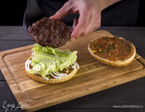 На одну половину булочки выложите несколько колец лука, закройте салатным листом, положите сверху котлету.