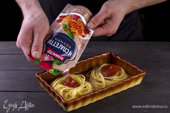 В смазанную маслом форму для запекания выложите спагетти в форме гнезд. Наполните их кетчупом к спагетти «Кухмастер». Посыпьте тертым сыром.