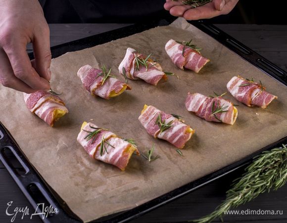 Картофельные дольки оберните в ломтики бекона, посыпьте розмарином и запекайте в духовке при 200°C полчаса.