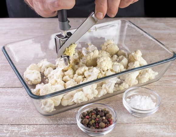 Пропустите через пресс чеснок, посыпьте им цветную капусту, посолите, поперчите.