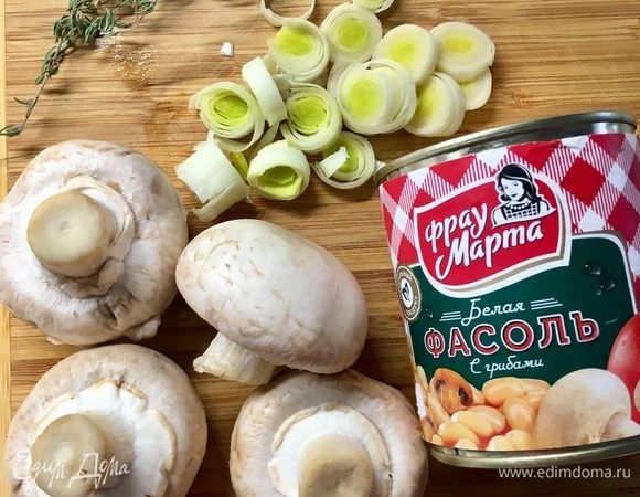 Теперь займемся вкусной весенней начинкой. Салат действительно получился интересный по вкусовой гамме. Сперва нарезать колечками небольшую палочку лука-порея. Шампиньоны помыть и обсушить. Сразу подготовить консервированную белую фасоль с грибами ТМ «Фрау Марта». Очень вкусную, между прочим, нежную и бархатистую фасоль. Можно есть просто так из баночки, но мы ей сейчас еще более дружественную компанию приготовим.