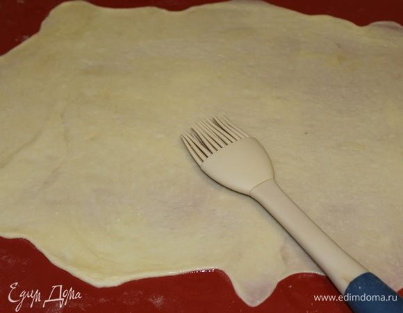 На столе раскатайте кусочек теста в тонкий, практически прозрачный пласт прямоугольной формы. Смажьте всю поверхность сливочным маслом.