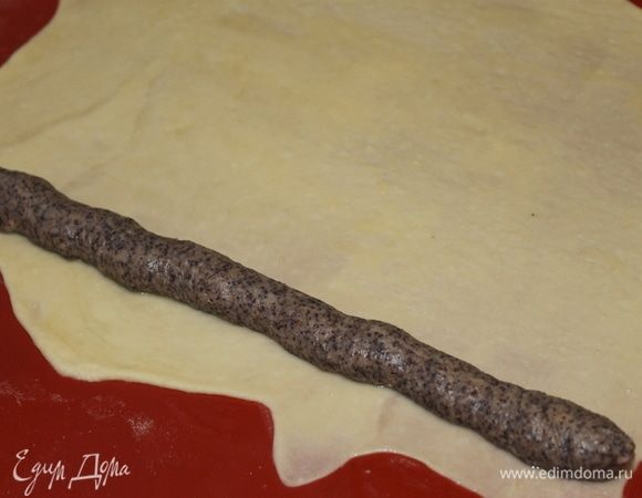 В кондитерский мешок положите начинку и выложите ее по длинной стороне пласта.