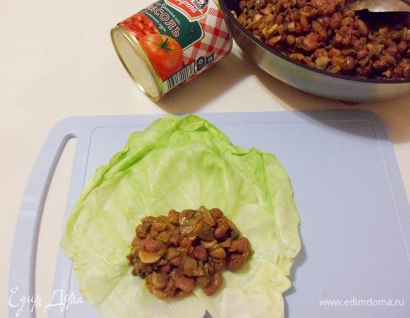 Отвариваем листья капусты в кипящей воде около 2 минут. Затем откидываем на сито, чтобы вся лишняя вода стекла. Теперь выложим на лист капусты фасолево-грибной фарш и завернем конвертиком.