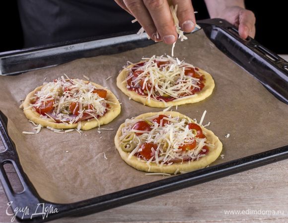 Выложите слой из ломтиков ветчины, посыпьте тертым сыром, украсьте черри и оливками.