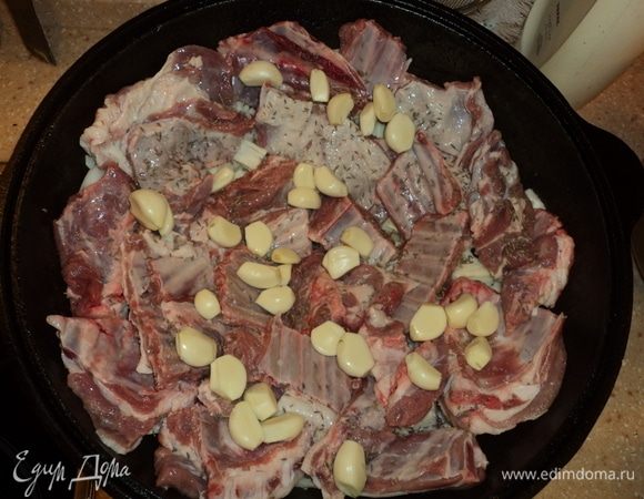 Первую половину мяса уложили (ту, что с жирком и косточками), чесноком посыпали, посолили, специи добавили.