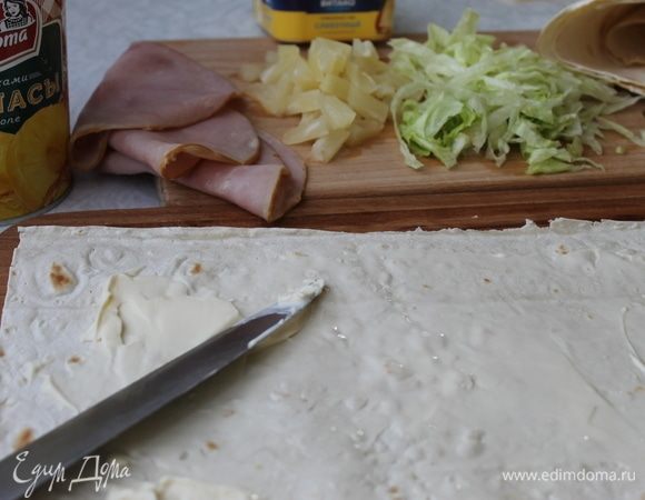 Нарежьте небольшими кусочками ананасы, айсберг нарежьте ленточками или нарвите небольшими кусочками. Лаваш смажьте тонким слоем сливочного сыра.