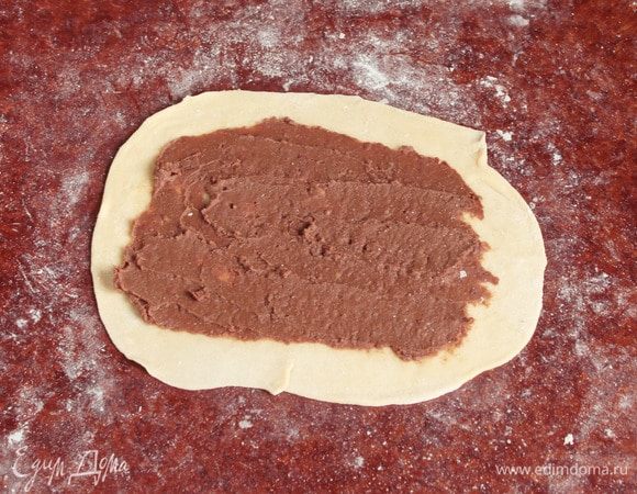 Отдохнувшее тесто разделить на 8 равных частей. Каждую раскатать в тонкий прямоугольный пласт на припыленной мукой поверхности. На каждый нанести примерно по 1 ст. л. начинки из фасоли. Размазать аккуратно начинку тонким слоем.