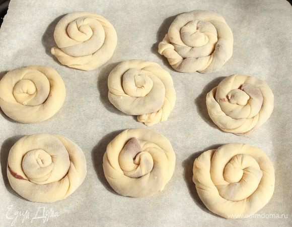 Колбаски слегка покрутить в жгутики и свернуть спиральками. Кончик заправить под спиральку. Выложить на застеленный пергаментом противень.