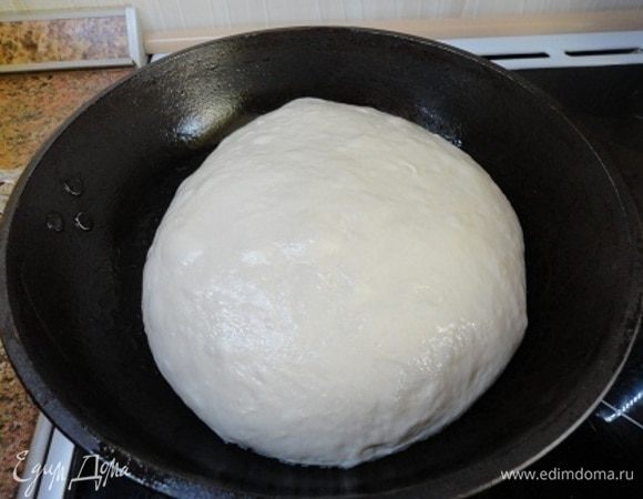 Подошедшее тесто разделить на две части. Вначале руками размять, потом завернуть края в середину и выложить швом вниз.