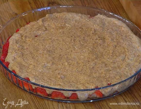 Разрезать пополам 500 г клубники и выложить в большую форму для выпечки плоской стороной вниз, сверху равномерно распределить миндальную массу и выпекать в разогретой духовке 20 минут.