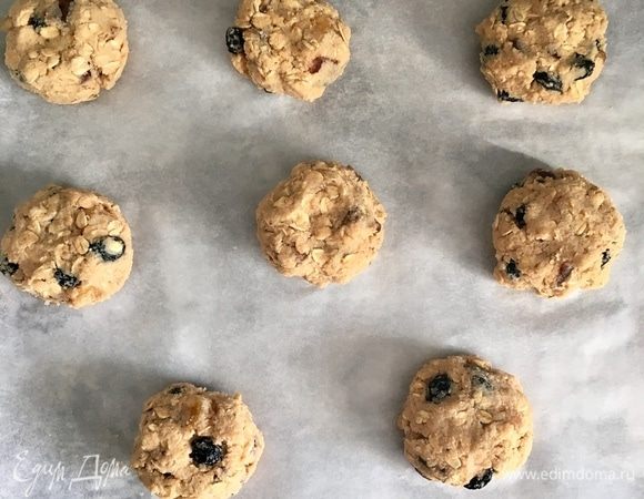 Из теста сформировать руками, смоченными в воде, шарики величиной чуть больше грецкого ореха, немного приплющить сверху. Противень застелить бумагой для выпечки и выложить печенье. Духовку разогреть до 180°C и печь около 20 мин.