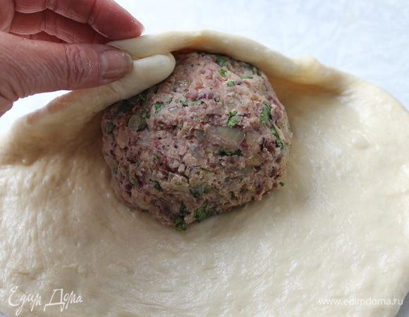 Возьмите один шар теста, прижимая руками, превратите его в круглую лепешку толщиной 1 см. Старайтесь края лепешки сделать тоньше, чем середина. На середину лепешки положите шар начинки и, поднимая края, закройте ее тестом.
