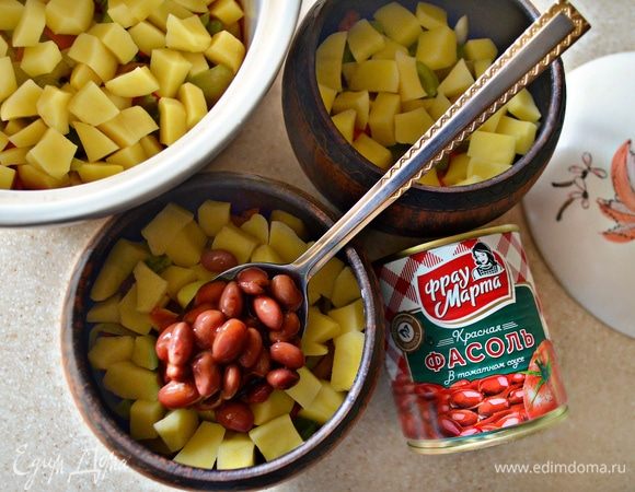 После чего уложить в горшочки очищенный и нарезанный небольшими кубиками картофель, слегка подсолить и поперчить. И затем сверху выложить вместе с соусом фасоль. Можно добавить по 2 ст. л. в каждый горшочек воды. Накрыть горшки крышками и поставить в духовку. Готовить в течение 1 часа 30 минут, при температуре 170 °C.