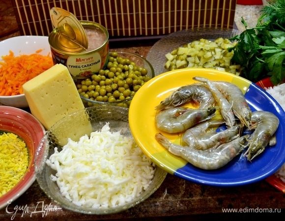 Готовим ингредиенты для салата. Рис промываем, затем перекладываем в кастрюльку и заливаем водой. Отвариваем рис до готовности аль денте. Перекладываем на сито и промываем под холодной водой. Вода с риса должна стечь. Маринованные огурцы перекладываем на разделочную доску, нарезаем их кубиками. Отварные куриные яйца натрем на терке, отдельно белки и желтки. Отварную морковь натрем на крупной терке. Сыр натрем на мелкой терке. И только ТМ «Магуро» позаботилось о нас и приготовили нам баночку салатного тунца, остается ее только открыть и слить масло с рыбы. Креветки очистить, оставить только хвостики.