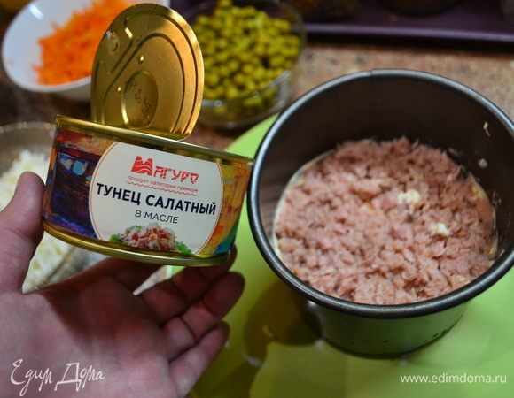 Начинаем выкладывать салат слоями. Первым слоем выложите отварной рис, хорошо смажьте майонезом. Вторым слоем будут располагаться огурцы. Третьим слоем идет опять рис и майонез. Четвертым слоем идет тунец ТМ «Магуро». Пятый слой — белок яйца. Шестой — морковь. Седьмой слой — сыр. Восьмой — желток. Сверху украсим креветками. Снизу — зеленью и горошком.