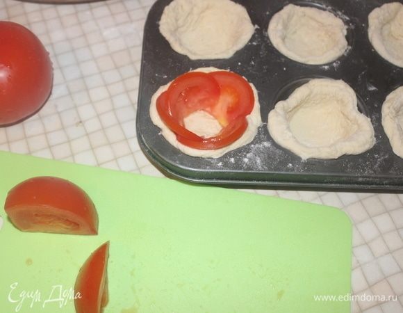 Нарезаем помидор полукольцами и выкладываем по бокам теста.