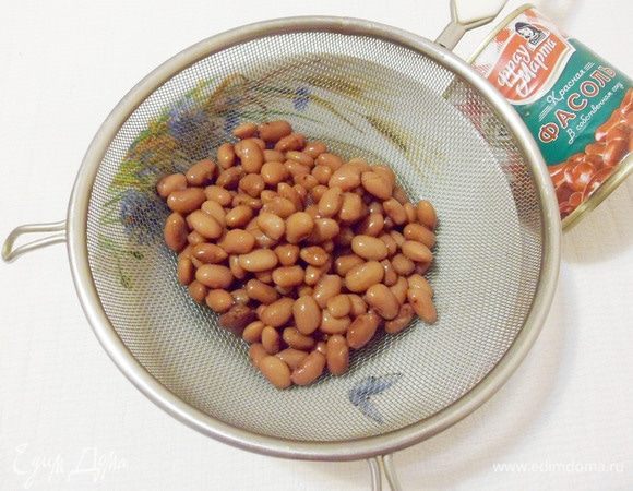 Консервированную фасоль откинуть на дуршлаг.
