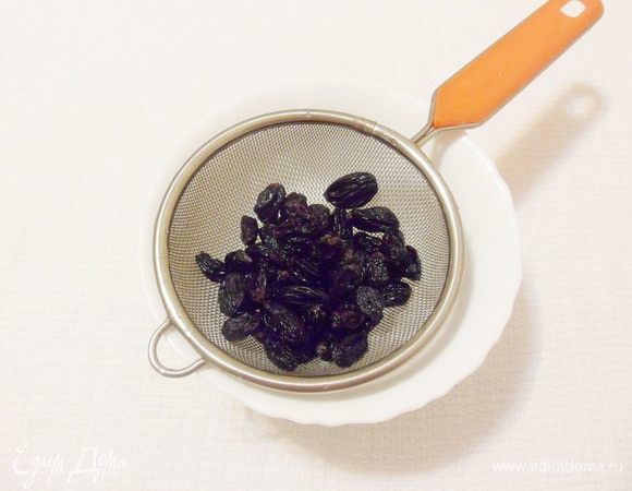 Черный изюм без косточек замочить в горячей воде на 15–20 минут, затем откинуть на ситечко.