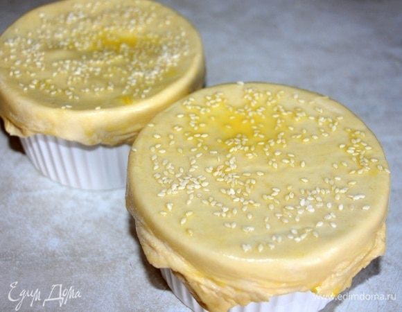 Слоеное тесто нарезать на квадраты, закрыть им верх формочек, смазать желтком и посыпать кунжутом. Накрыть фольгой и запекать при температуре 180 °C 25 минут. За 5 минут до готовности убрать фольгу и запекать до золотистой корочки.